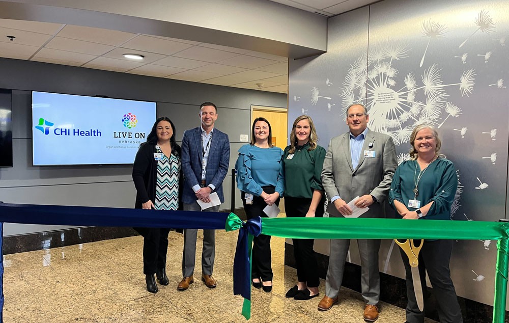 Group cutting ribbon in front of donor wall